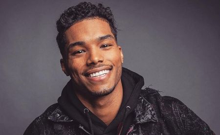 Rome Flynn cheerfully poses for the camera with a big smile.